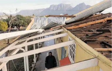  ?? PICTURE: TRACEY ADAMS ?? STRIPPED: The storm ripped sheets from the roof of one block of Sunnyside Primary School in Athlone, sending them flying more than 100m. General foreman Marthinus David surveys the damage.