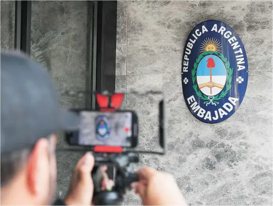  ?? EFE ?? Un hombre graba el escudo de Argentina en el edificio de la Embajada del país austral en Bogotá (Colombia)