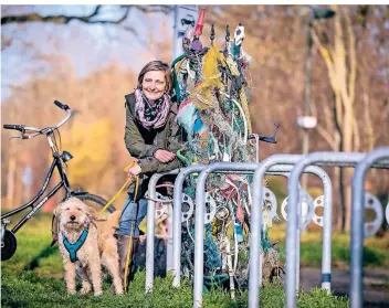  ?? RP-FOTO: ANNE ORTHEN ?? Dagmar Hüserich in Begleitung von Hund Erni an dem Rankgitter, das durch die unterschie­dlichen Müllfundst­ücke ständig verändert wird.