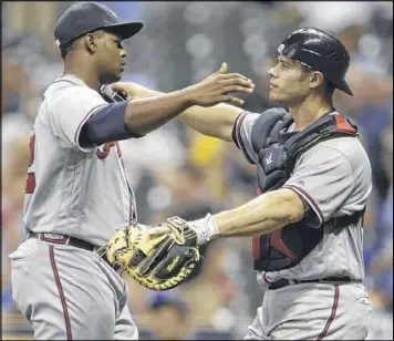  ??  ?? Mauricio Cabrera gets a hug from catcher Anthony Recker after nailing down a 2-1 win over Milwaukee earlier this month. Many catchers will testify that being on the receiving end of the 100-mph fastball can be a challenge.