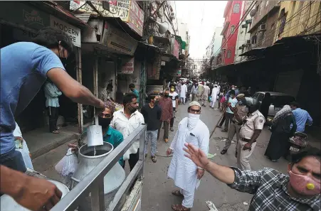  ?? MANISH SWARUP / ASSOCIATED PRESS ?? Indian Muslims queue up to buy milk during a three-hour relaxation of restrictio­ns to buy essential items during the holy month of Ramadan in the old quarter of Delhi on Saturday. The country’s lockdown, which Prime Minister Narendra Modi announced on March 25, has been extended until this Sunday.