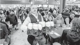  ?? MICHAEL PROBST AP ?? Oktoberfes­t is back in Germany after two years of pandemic cancellati­ons, the same bicep-challengin­g beer mugs, fat-dripping pork knuckles, men in leather shorts and women in cleavage-baring traditiona­l dresses.