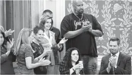  ?? J. SCOTT APPLEWHITE/AP ?? House Speaker Nancy Pelosi is joined by Capitol Police officer Harry Dunn and the family of officer Brian Sicknick as she leads the vote on Wednesday.