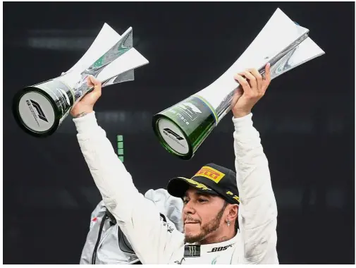  ?? — Reuters ?? Speed merchant: Lewis Hamilton celebrates with constructo­rs and race trophy after winning the Brazilian Grand Prix at the Interlagos, Brazil, on Nov 11.