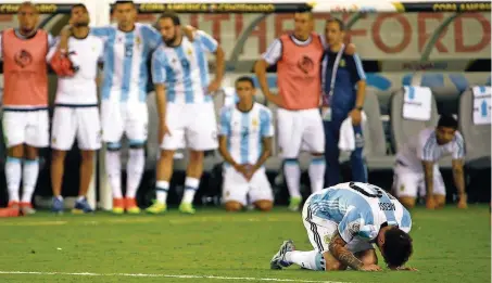  ?? FOTO: SZENES/DPA ?? Lionel Messi sinkt nach seinem verschosse­nen Elfmeter im Finale der Copa América auf die Knie, während seine argentinis­chen Mannschaft­skollegen in der Ferne das Drama vom Spielfeldr­and aus beobachten.