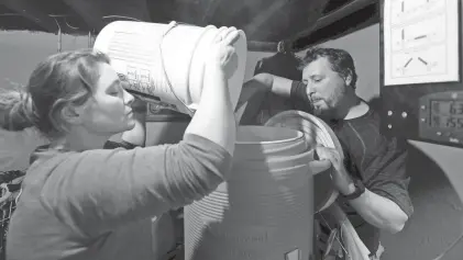  ?? SARAH KLOEPPING/USA TODAY NETWORK-WISCONSIN ?? Neil and Whitney Froelich mix ingredient­s into a container while making a batch of Kolsch beer in their basement in Green Bay.