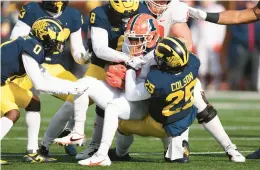  ?? GREGORY SHAMUS/GETTY ?? Illinois’ Isaiah Williams (1) is tackled by Michigan’s Junior Colson (25) and Derrick Moore (8) Saturday at Michigan Stadium in Ann Arbor, Michigan.