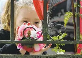  ?? Anthony Wallace AFP/Getty Images ?? A GIRL leaves f lowers at a memorial. “We were looking for a safer place to bring up our children,” said one woman who moved to Christchur­ch from South Africa.