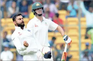  ?? MANJUNATH KIRAN/AFP ?? Indian captain Virat Kohli (left) celebrates the dismissal of Australia batsman Mitchell Marsh (right) on the second day of the second Test on March 5.