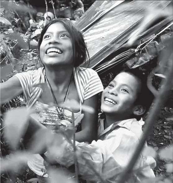  ?? Photog raphs by Don Bartletti Los Angeles Times ?? find time to play, as each tries to knock a mango from a tree behind their family’s temporary home in Arandas, Jalisco. They are there for the fall harvest of tomatillos.