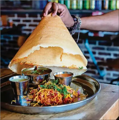  ?? CONTRIBUTE­D BY HENRI HOLLIS ?? The Bollywood Masti at Indian street food restaurant Masti includes a hat-shaped dosa served over butter chicken, tomato stew and two chutneys for dipping.