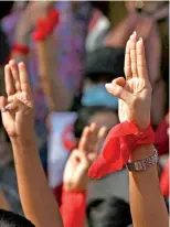  ??  ?? Protesters hold up the three finger salute.