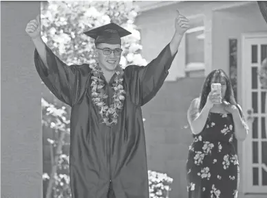  ?? CHERYL EVANS/THE REPUBLIC ?? Angel Queiro celebrates his high school graduation in a driveway commenceme­nt ceremony.