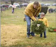  ?? LAUREN A. LITTLE — MEDIANEWS GROUP ?? Thomas Ashman of Cumru Township helps his son, Owen, age 3, lay a wreath during Wreaths Across America at Forest Hills Memorial Park.