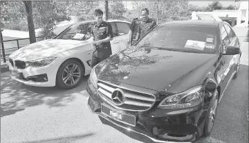  ??  ?? Mazelan (left) inspecting two of the vehicles seized in the operation. — Bernama photo