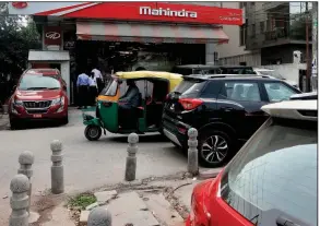  ?? (AP) ?? A three-wheeler passes a Mahindra and Mahindra showroom in New Delhi in this file photo. Ford, which had a partnershi­p with Mahindra, said Thursday that it will cease auto production in India.