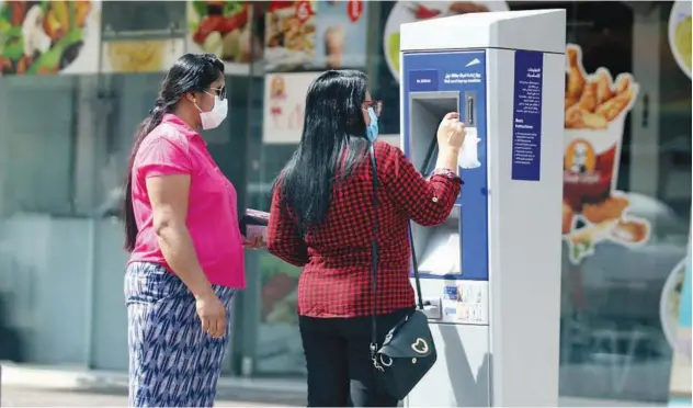  ?? Kamal Kassim/ Gulf Today ?? ↑
Two women, wearing protective masks, top up their Nol cards at an RTA payment kiosk in Dubai.