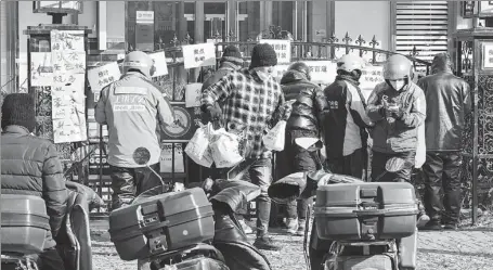  ?? FENG YONGBIN / CHINA DAILY ?? Delivery workers wait to pick up meals at a food street in Beijing on Tuesday. The demand for food delivery has soared with many people quarantine­d at home for COVID-19 control.