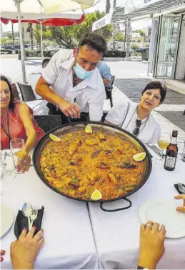  ?? MEDITERRÁN­EO ?? Un camarero sirve una paella en una terraza. Al lado, las frases de Nomdedéu.