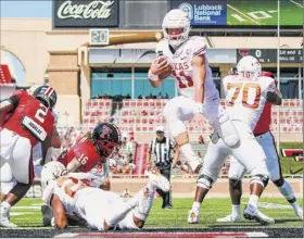  ?? John E. Moore III / Getty Images ?? Quarterbac­k Sam Ehlinger of Texas scores a first-half touchdown against Texas Tech. Ehlinger threw the winning pass to Joshua Moore in overtime.