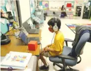 ?? EMILY MICHOT/MIAMI HERALD VIA AP ?? Nova Blanche Forman Elementary School teacher Attiya Batool teaches her 4th grade class virtually as her son, Nabeel, does his second grade classwork online wearing a face mask and headphones during the first day of school in Broward in Davie, Fla.