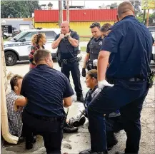  ?? KATIE WEDELL / STAFF ?? AFTERMATH OF AN OVERDOSE: Dayton Fire Department EMT Amy Dunkin (center, kneeling) and other first responders listen to a man June 12 who just had been revived with Narcan at a gas station on North Keowee Street.