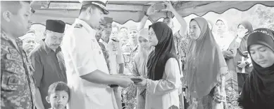  ?? — Gambar Bernama ?? SUASANA PILU: Siti Salbiah Roslie, balu kepada Mohamad Ikmal, menerima Jalur Gemilang sebaik jenazah suaminya selamat dikebumika­n di Tanah Perkuburan Islam Bukit Rangin semalam.