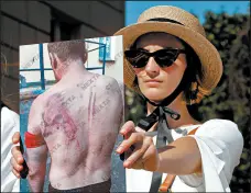  ?? DMITRI LOVETSKY/AP ?? A woman holds a photo of a protester beaten by police Saturday during a demonstrat­ion in Minsk, Belarus.