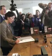 ?? THE ASSOCIATED PRESS ?? Rhode Island Gov. Gina Raimondo, left, signs a formal business citation at A.T. Cross Co.’s new flagship retail store on Wednesday in Providence, R.I. The 170-year-old maker of high-end pens recently moved its headquarte­rs to Providence from suburban...