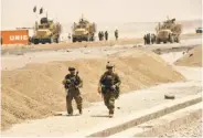  ?? Javed Tanveer / AFP / Getty Images ?? U.S. soldiers walk at the site of a Taliban suicide bomb attack on a NATO convoy in Kandahar.