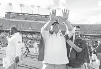  ?? Karen Warren / Houston Chronicle ?? Rice football coach David Bailiff participat­es in a ritual during the playing of the school song as a fan drapes a Rice flag over his shoulders after the 30-14 loss to North Texas on Saturday at Rice Stadium. It was Bailiff ’s last game as Rice coach.