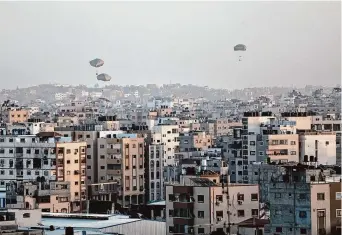  ?? Mohammed Hajjar/Associated Press ?? Humanitari­an aid is dropped by the United States over Gaza City on Saturday.
