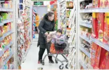  ?? — AFP ?? A woman uses a trolley carrying a boy at a supermarke­t in Beijing, China.