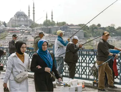 ?? ?? People walk along the Galata Bridge, with the Suleymaniy­e Mosque in the background, two days after the first round of the Turkish general elections, in Istanbul, Tuesday. The second round will be held on May 28.