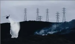  ?? JEFF CHIU — THE ASSOCIATED PRESS FILE ?? A helicopter drops water near power lines and electrical towers while working at a fire on San Bruno Mountain near Brisbane.