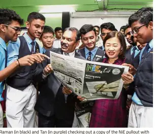  ??  ?? Raman (in black) and Tan (in purple) checking out a copy of the NiE pullout with students.