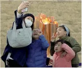  ??  ?? In Giappone Il sacro fuoco di Olimpia è arrivato ieri in Giappone con un volo speciale: i fan si fanno selfie con la fiamma (Getty Images, Epa)