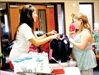  ?? LYNN KUTTER ENTERPRISE-LEADER ?? Rachel Lawrence, school counselor for Ledbetter Intermedia­te in Farmington, helps Tina Atkinson, 10, of West Fork find a new backpack. Tina attends school in Prairie Grove. See more photos on Page 7A.