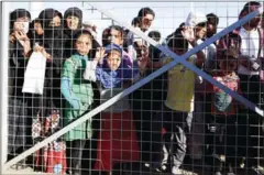  ?? THOMAS COEX/AFP ?? Iraqi refugees wait behind a fenced gate for food distributi­on on Monday at the Khazir refugee camp after fleeing from Mosul.