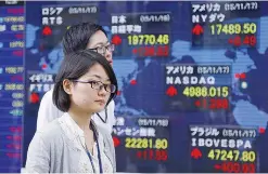  ??  ?? TOKYO: People walk past an electronic stock indicator of a securities firm in Tokyo yesterday. Asian stocks were mostly higher yesterday as the shock of the Paris terror attacks faded and an uptick in US inflation added support for a possible interest...