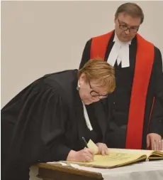  ??  ?? Lorna Cottenden, left, signs the register after taking her oath with Justice Darin Chow at the Bar Admission Ceremony Thursday at the Court of Queen’s Bench in Moose Jaw. Matthew Gourlie photograph