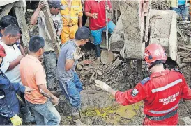  ?? [FERNANDO VERGARA/THE ASSOCIATED PRESS] ?? Firefighte­rs and neighbors stop their work as they found the body of a woman Sunday in Mocoa, Colombia. Colombia’s President Juan Manuel Santos, who has declared Mocoa a disaster area, said that at least 207 were killed but that the death toll was...