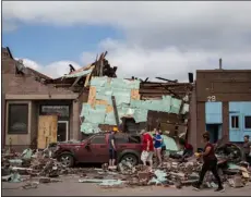  ??  ?? A group of people work to clear rubble surroundin­g a car in downtown Marshallto­wn, Iowa, on Saturday. KelSey Kremer/The DeS moIneS regISTer VIA AP