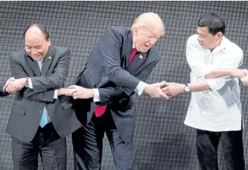  ?? JIM WATSON/GETTY IMAGES ?? Vietnam’s Prime Minister Nguyen Xuan Phuc, left, U.S. President Donald Trump and Philippine President Rodrigo Duterte join hands for a photo during the 31st Associatio­n of South East Asian Nations Summit on Monday.