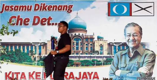  ??  ?? Back in power: A man walking past a banner of Dr Mahathir on Langkawi Island. — Reuters
By ARNOLD LOH arnold.loh@thestar.com.my