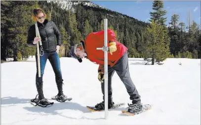  ?? Rich Pedroncell­i ?? The Associated Press Frank Gehrke, chief of the California Cooperativ­e Snow Surveys Program for the Department of Water Resources, checks the depth of the snowpack as Karla Nemeth, director of DWR, looks on Monday during the snow survey near Echo...