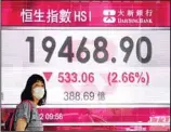  ?? (AP) ?? A woman wearing a face mask walks past a bank’s electronic board showing the Hong Kong share index in Hong Kong, Tuesday, May 10, 2022. Asian stocks followed Wall Street lower Tuesday as fears increased that U.S. rate hikes to fight inflation might stall economic growth.