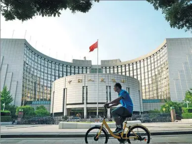  ?? FAN SHAOGUANG / FOR CHINA DAILY ?? A cyclist pedals past the headquarte­rs of the People’s Bank of China in Beijing.