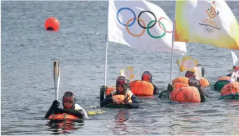  ?? —AP ?? Woman diver Haenyeo carries the torch during the Olympic Torch Relay in waters of Jeju Island, South Korea on Friday.