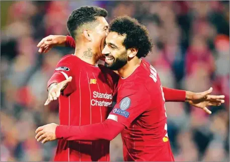  ?? PAUL ELLIS/AFP ?? Liverpool’s Mohamed Salah (right) celebrates with Roberto Firmino after scoring their fourth goal during the Uefa Champions League Group E football match against Salzburg at Anfield Stadium in Liverpool, north west England, on Wednesday.